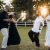 Group of friends dancing and enjoying a summer evening outdoors with drinks in hand.